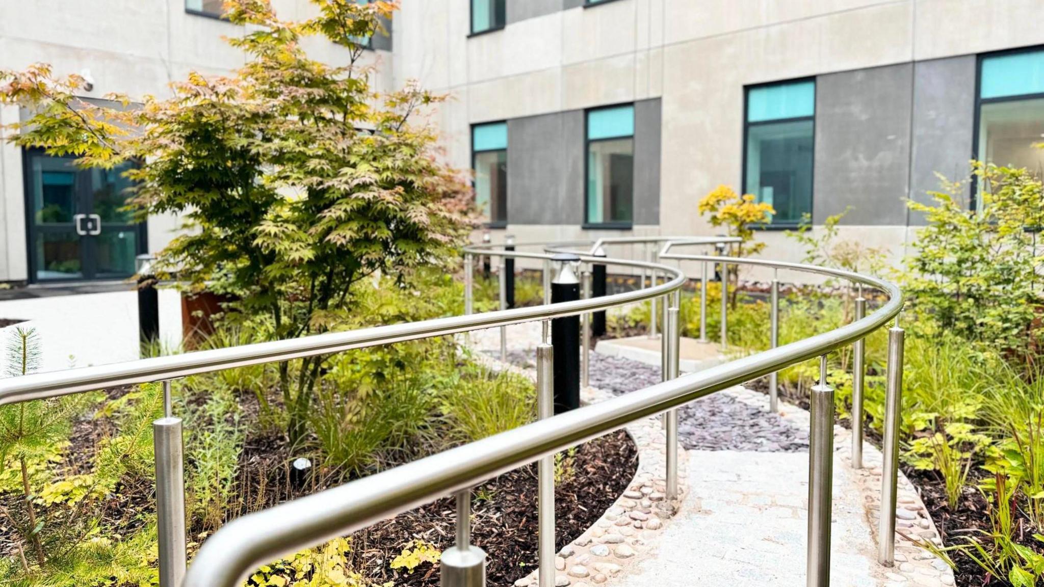 The internal courtyard has a white stone pathway running down the middle with a metal barrier on either side. Shrubbery has been planted alongside.