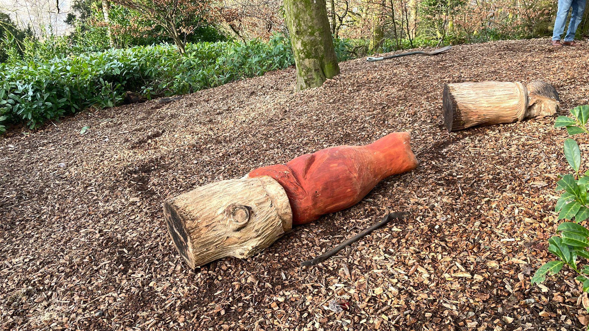 One of the carvings, of a stick-like character, is lying on its side in the forest