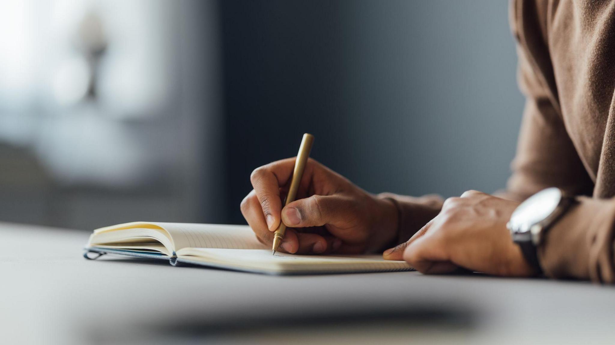 A man writing in a notebook. 