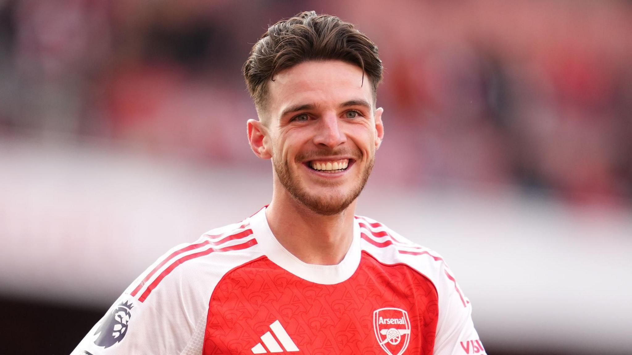 Declan Rice in an Arsenal football shirt. He is smiling.