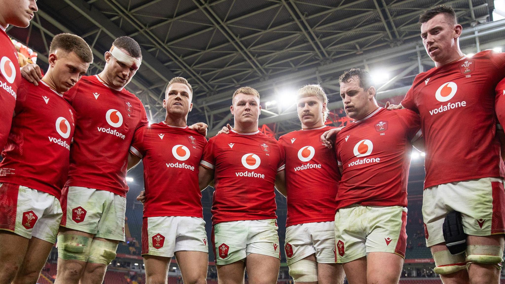 Wales players standing arm in arm in huddle