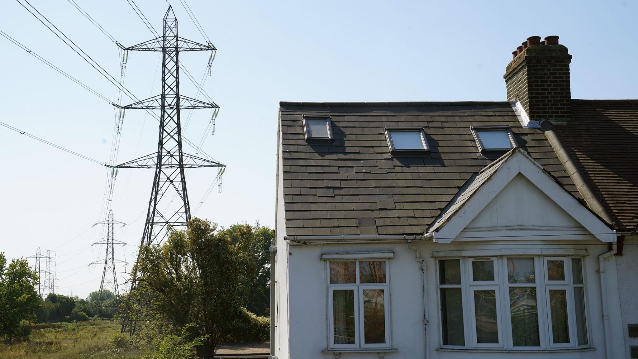 A white painted house with a line of electricity pylons beside it