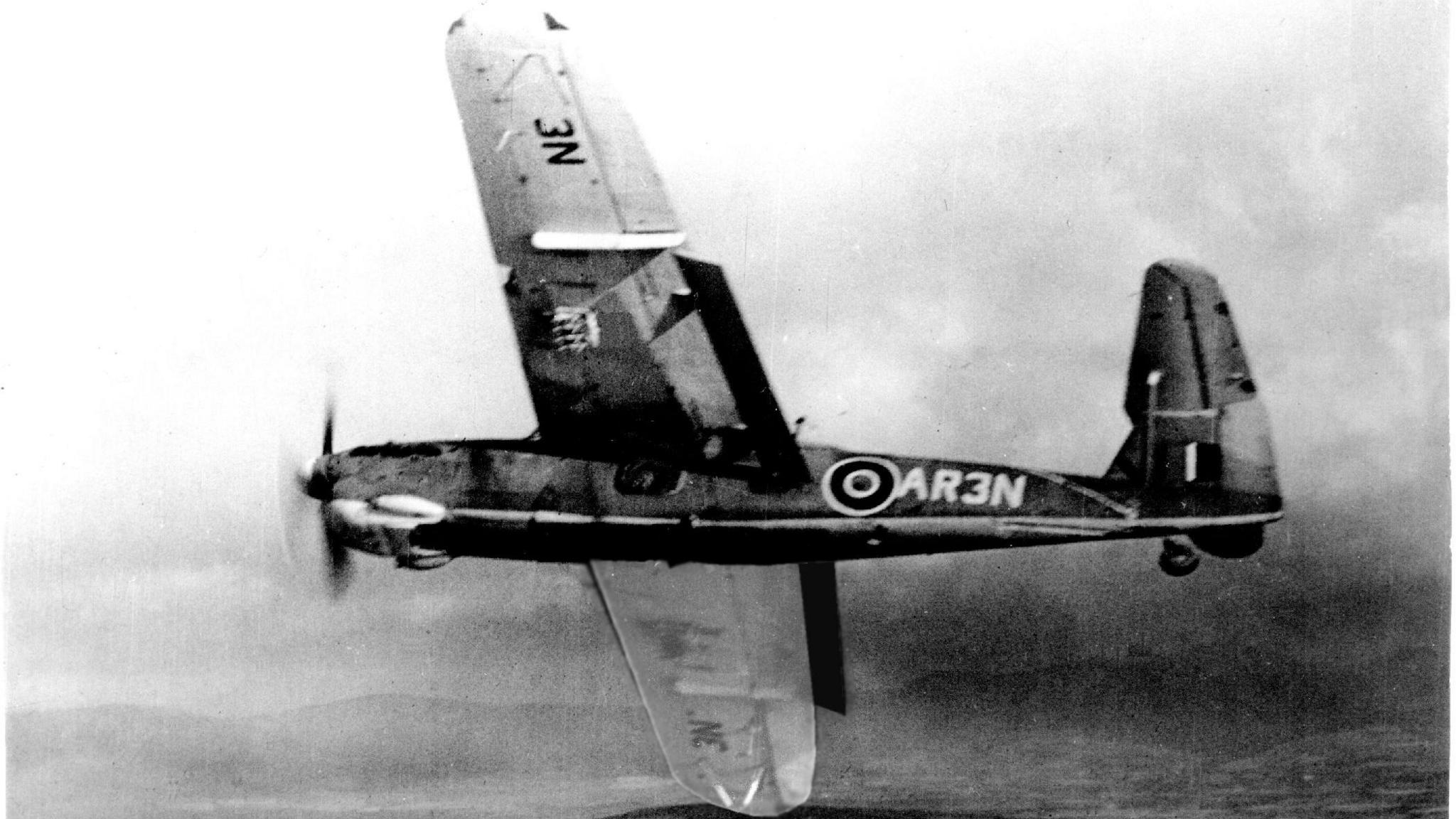 A black and white image of a Fairey Barracuda Torpedo Bomber in flight. The propeller on the nose of the plane is spinning and it has N3 on the underside of the left wing. AR3N is written on the body of the craft alongside the Royal Airforce logo. Its right wing is dipping into a turn.