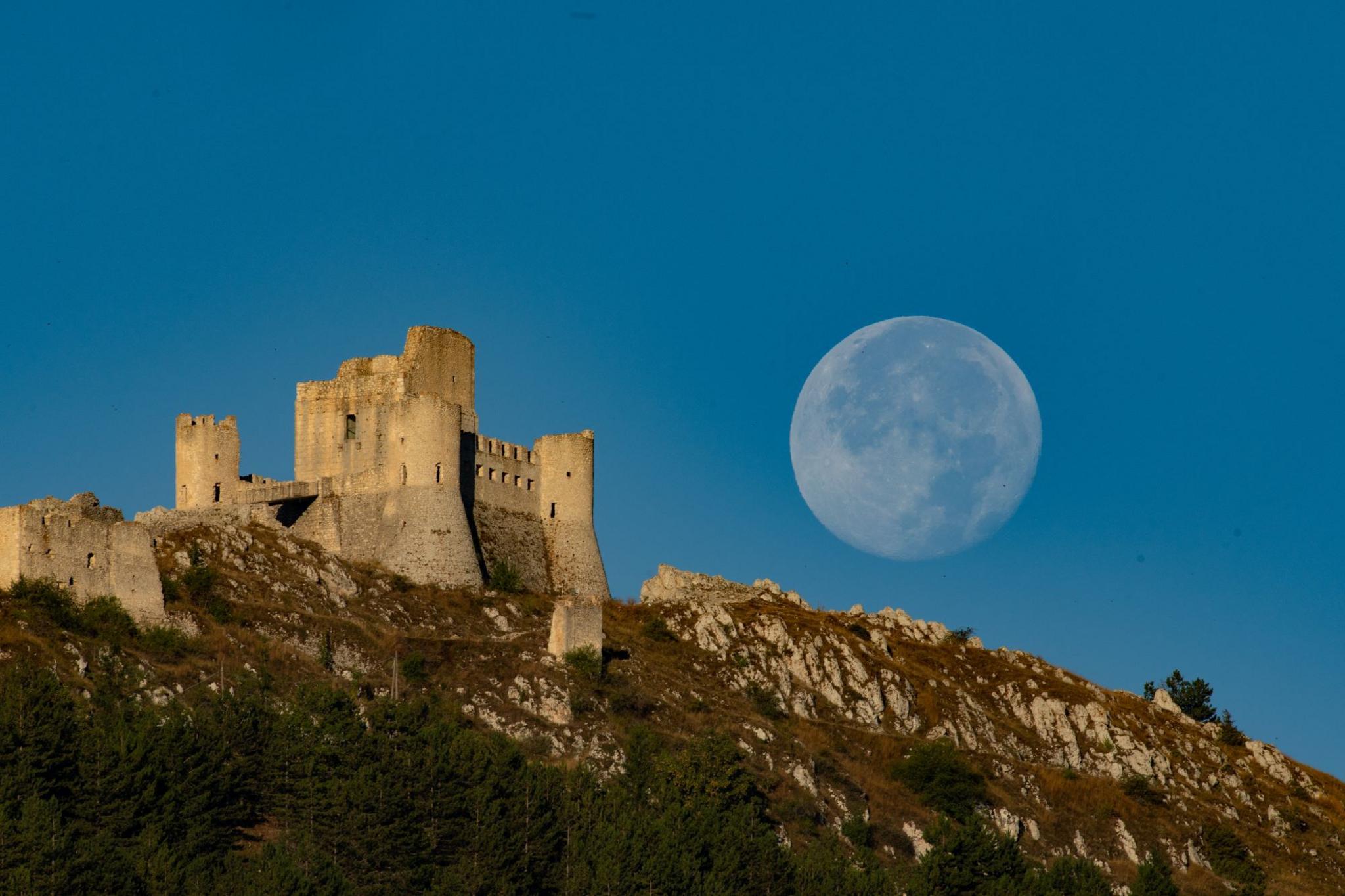 Supermoon setting behind Rocca Calascio Castle in Calascio, Italy