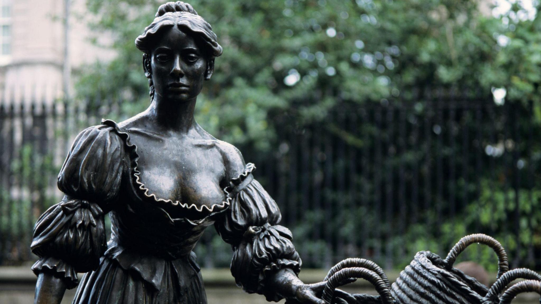 The statue of Molly Malone at its original site in Dublin's Grafton Street. The gates of Trinity College are in the background.