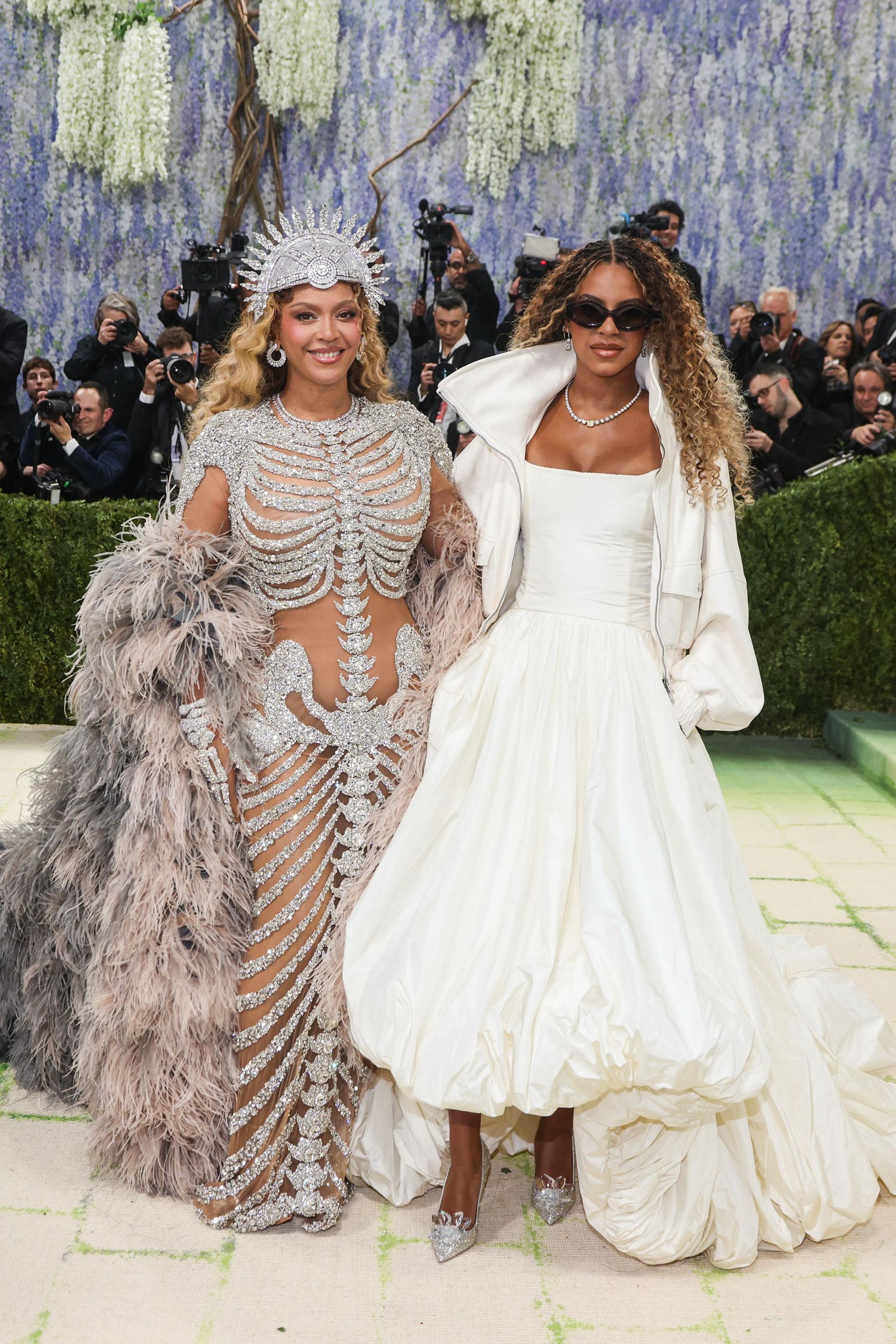 Beyoncé wears a sparkly silver outfit and headpiece, while Blue Ivy wears a white ballgown and white jacket. 