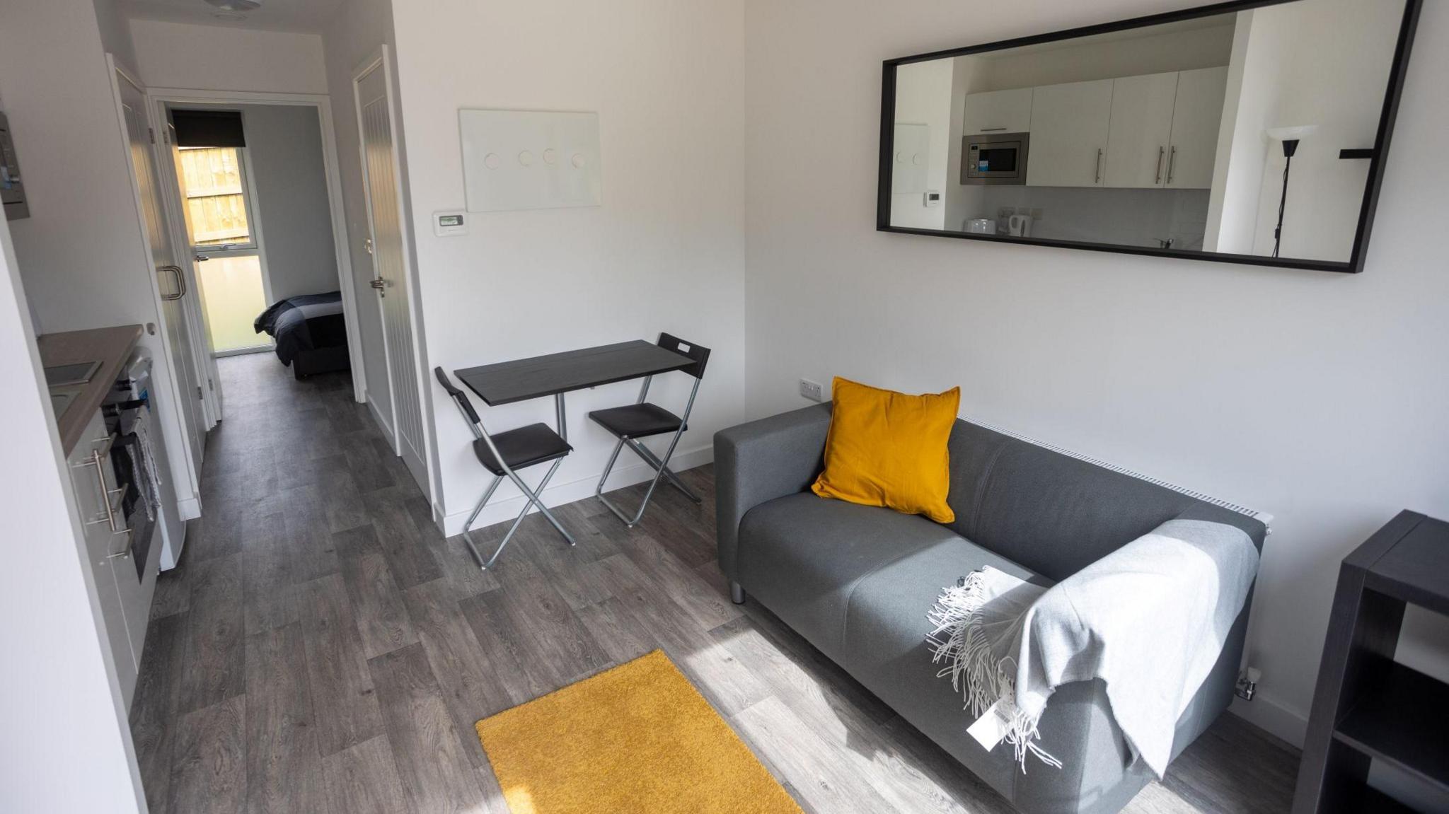 The lounge and kitchen area of one of the new homes, which has a table for two and a grey sofa