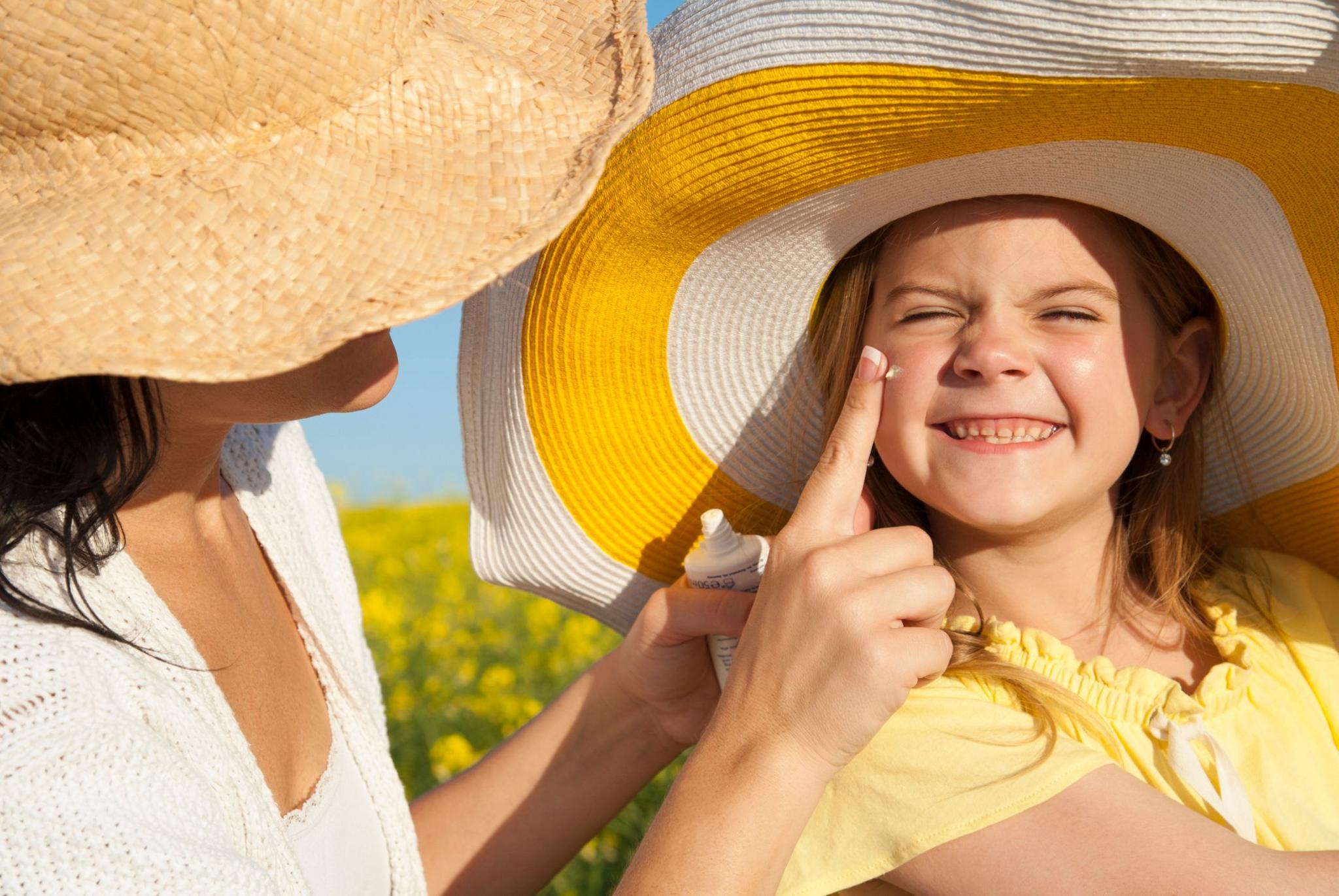 Girl having sun cream applied by an adult