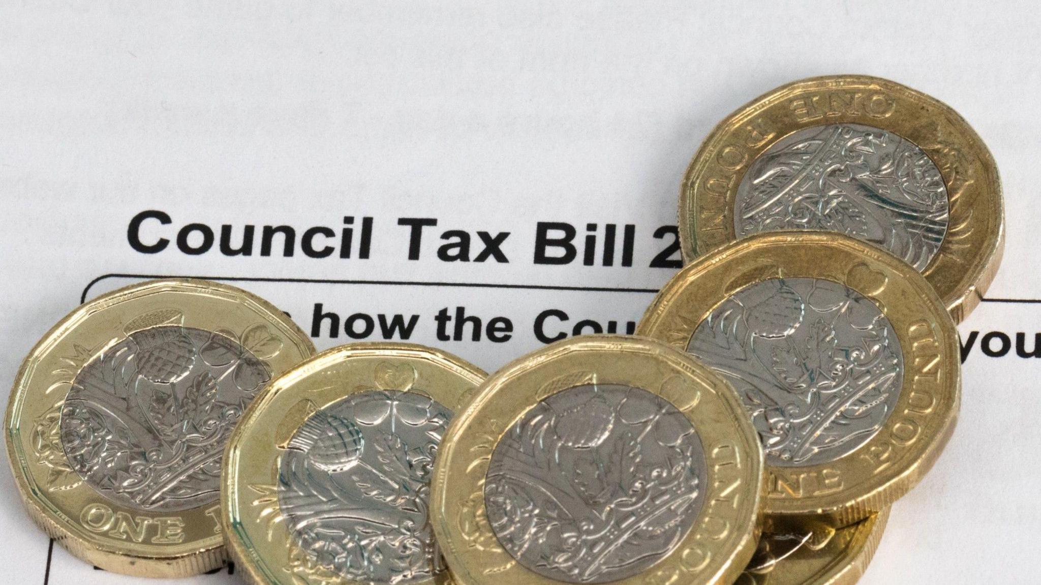 Six pound coins sitting on top of a council tax demand.