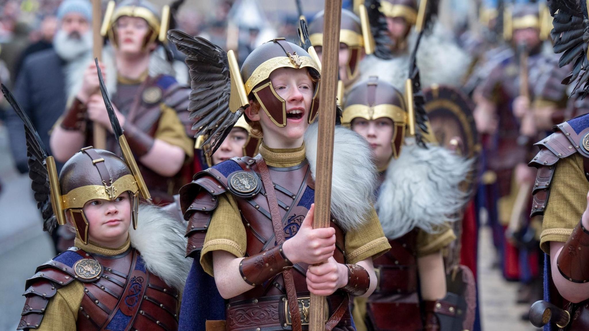 Young members of the Jarl Squad parade in Viking dress with helmets.