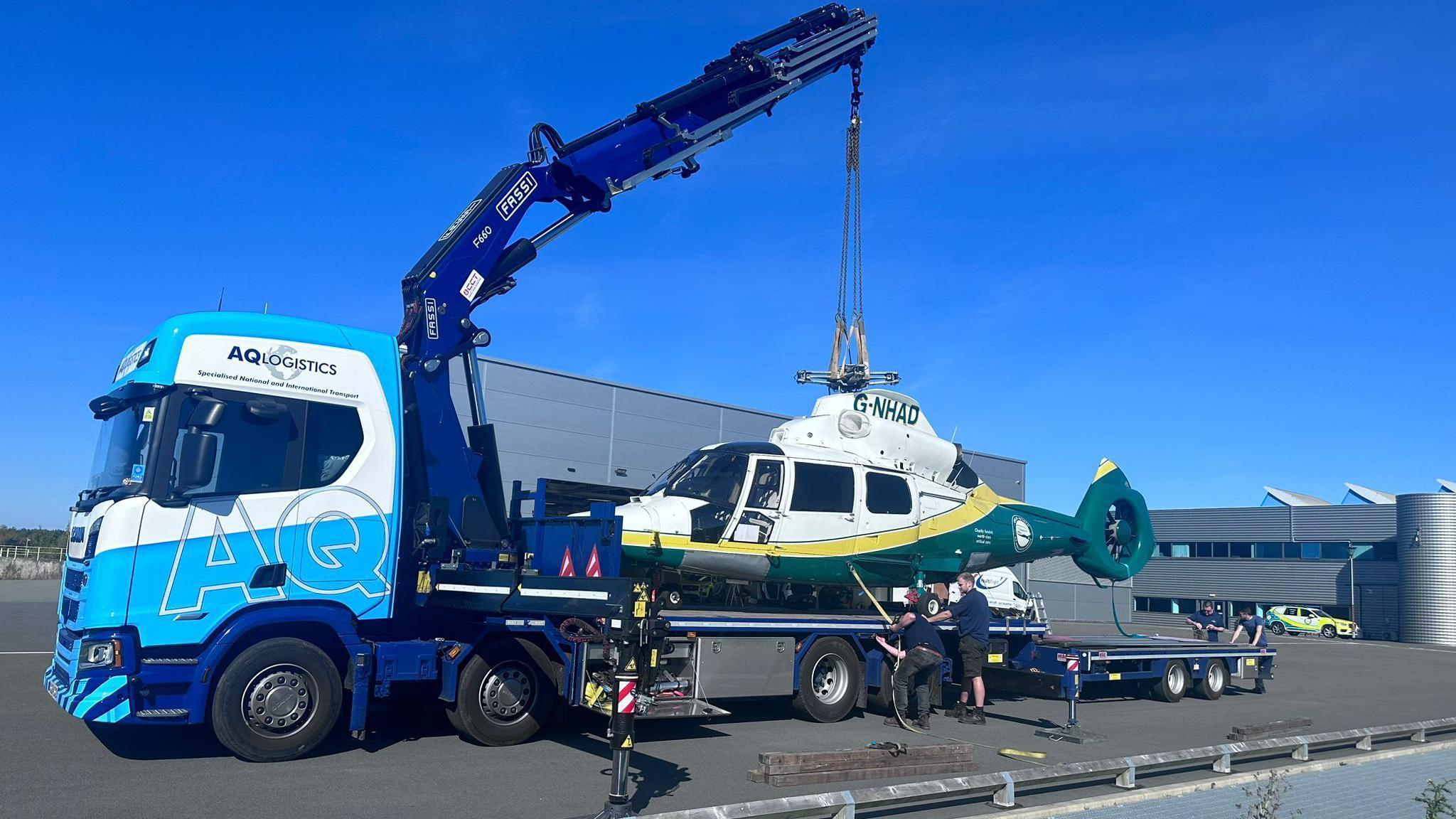 The Guardian of the North II helicopter being lifted on to the back of a lorry.