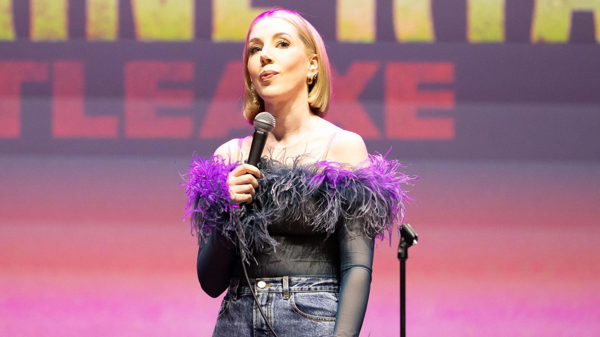 Katherine Ryan holding a microphone while performing in Brighton last month, wearing a frilly purple outfit