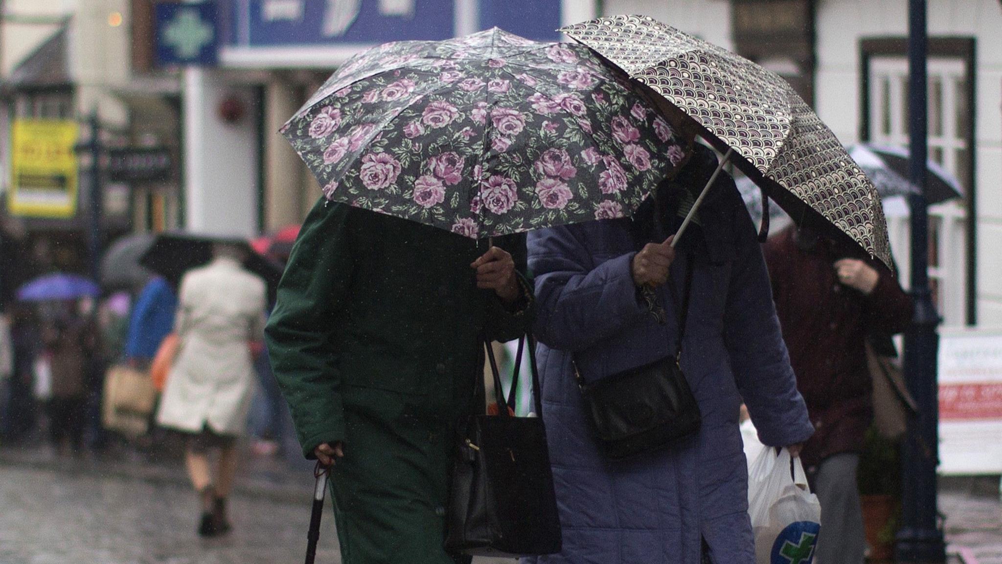 dwy ddynes yn cerdded yn y glaw