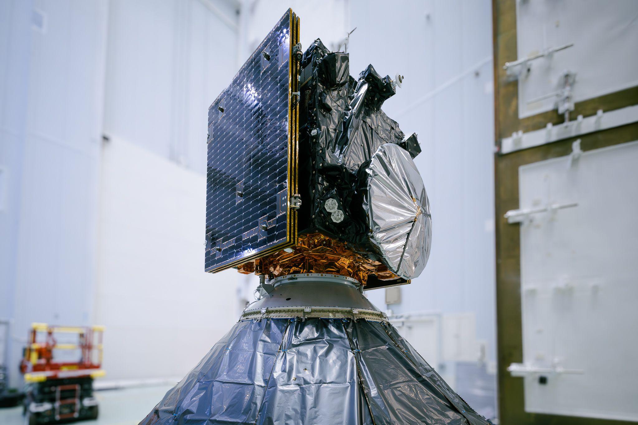 A last view of Hera in its launch configuration before being encapsulated within its Falcon 9 launcher fairing, resting atop its launcher adapter. All 'red tag' items have been removed and its solar arrays no longer have protective covers, and the spacecraft is fully wrapped in multi-layer insulation, including across its High Gain Antenna. 