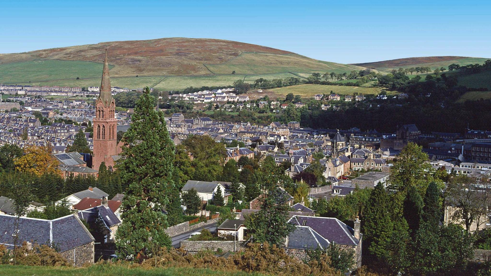 A view from the hillside over the Borders town of Galashiels with hundreds of rooftops and a church spire standing proud in the foreground