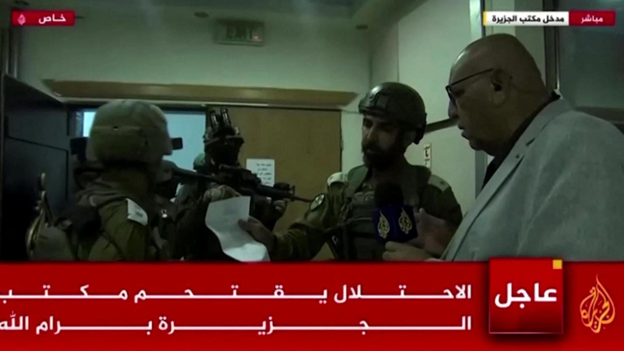 Screengrab of Al Jazeera TV broadcast showing Israeli soldiers handing over orders to bureau chief Walid al-Omari, at Al Jazeera's office in Ramallah, in the occupied West Bank (22 September 2024)