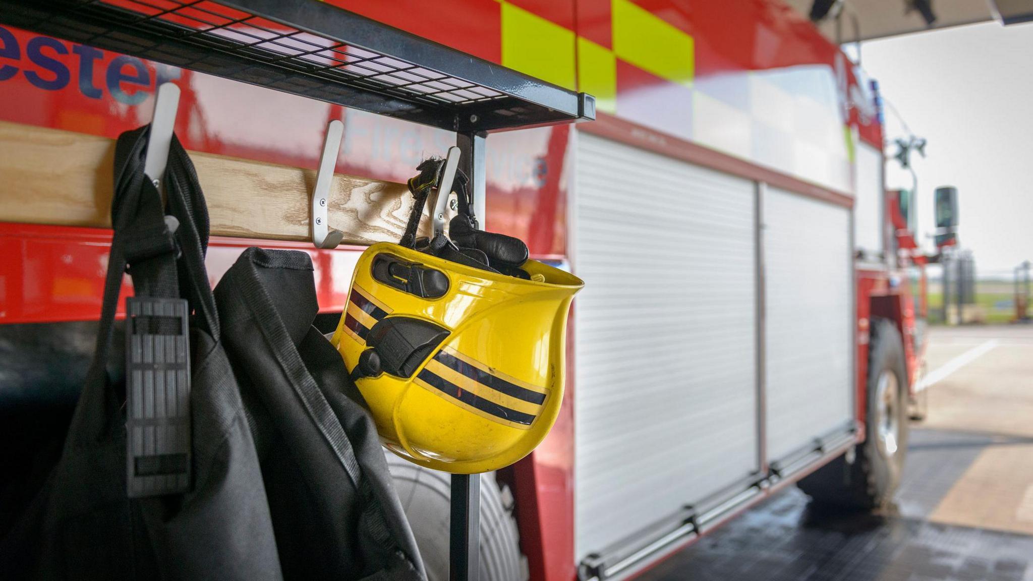 A stock shot showing a yellow firefighter's helmet hanging on the side of a red fire engine.