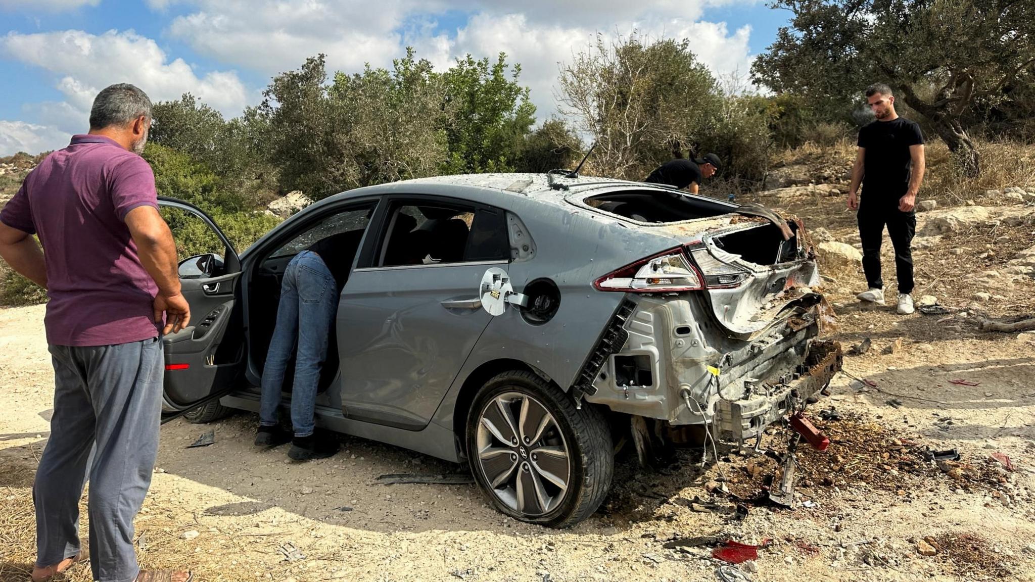 Palestinians assess damage to a car during a military operation by Israeli forces near Jenin, in the occupied West Bank (28 August 2024)