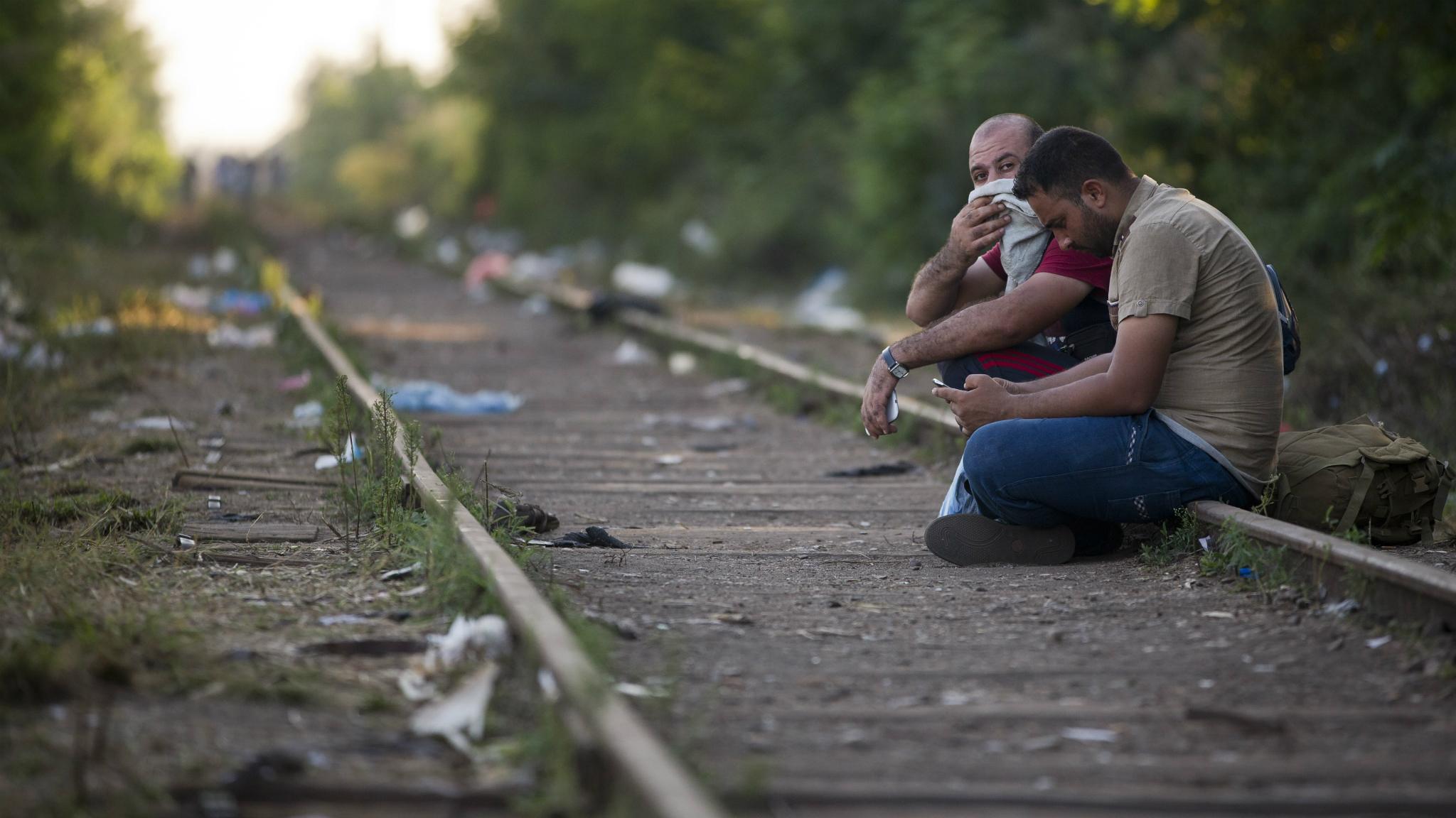 Two men sit on the railway track before crossing the border from Serbia into Hungary - 1 September 2015