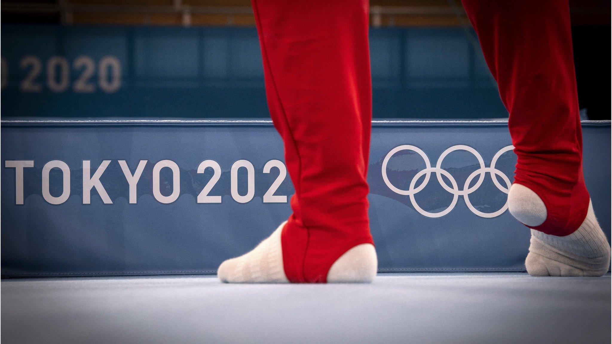 Gymnast in front of the Olympic logo