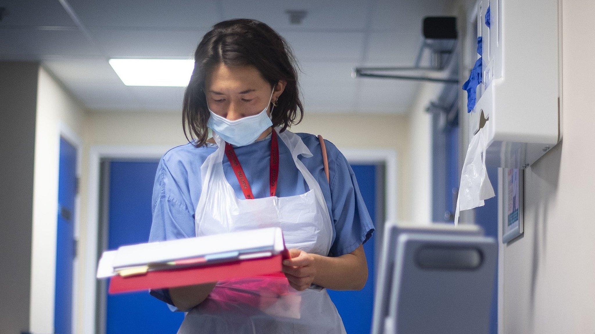 A doctor looks at a patient's notes at NHS Seacole Centre in Surrey