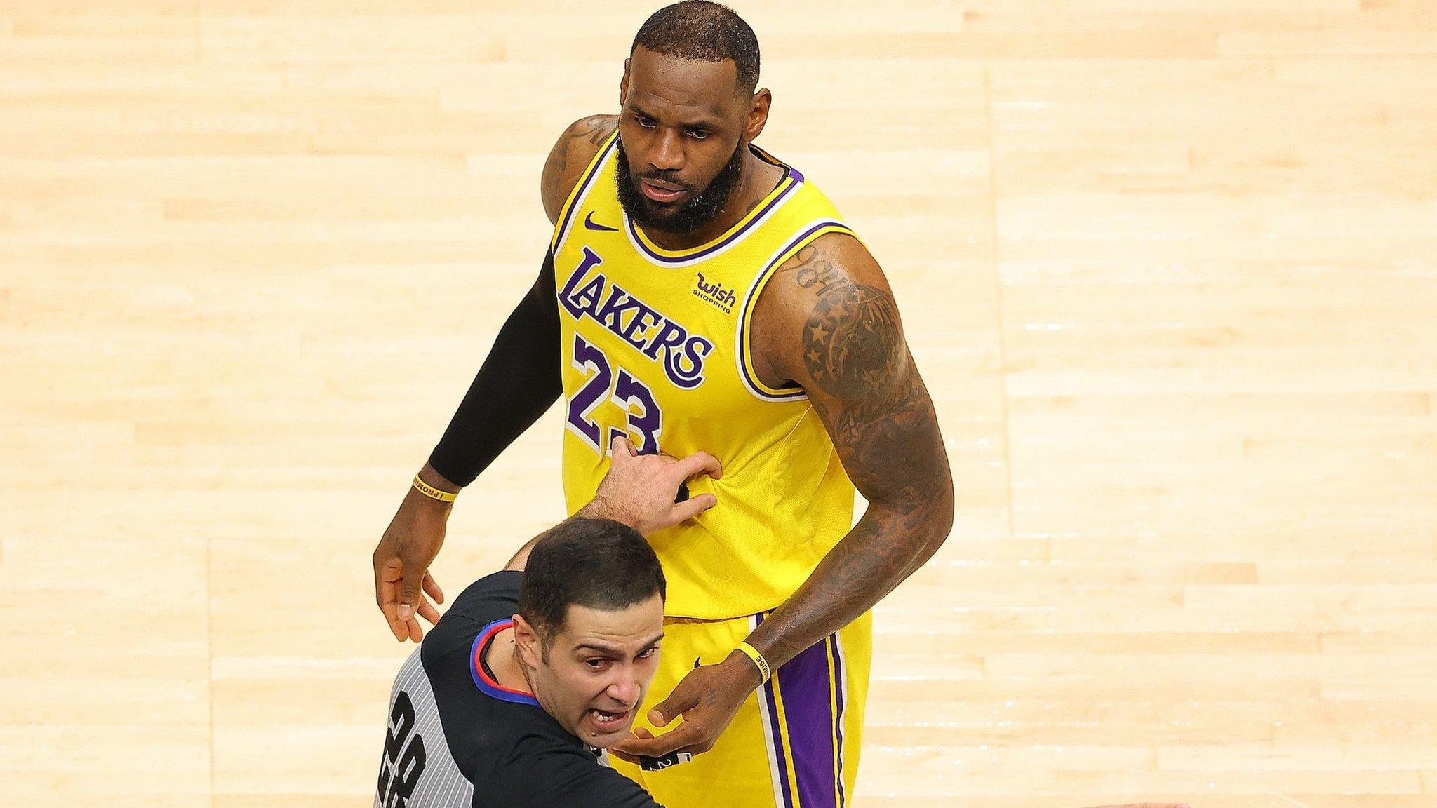 LeBron James and NBA official Mousa Dagher look at a fan courtside