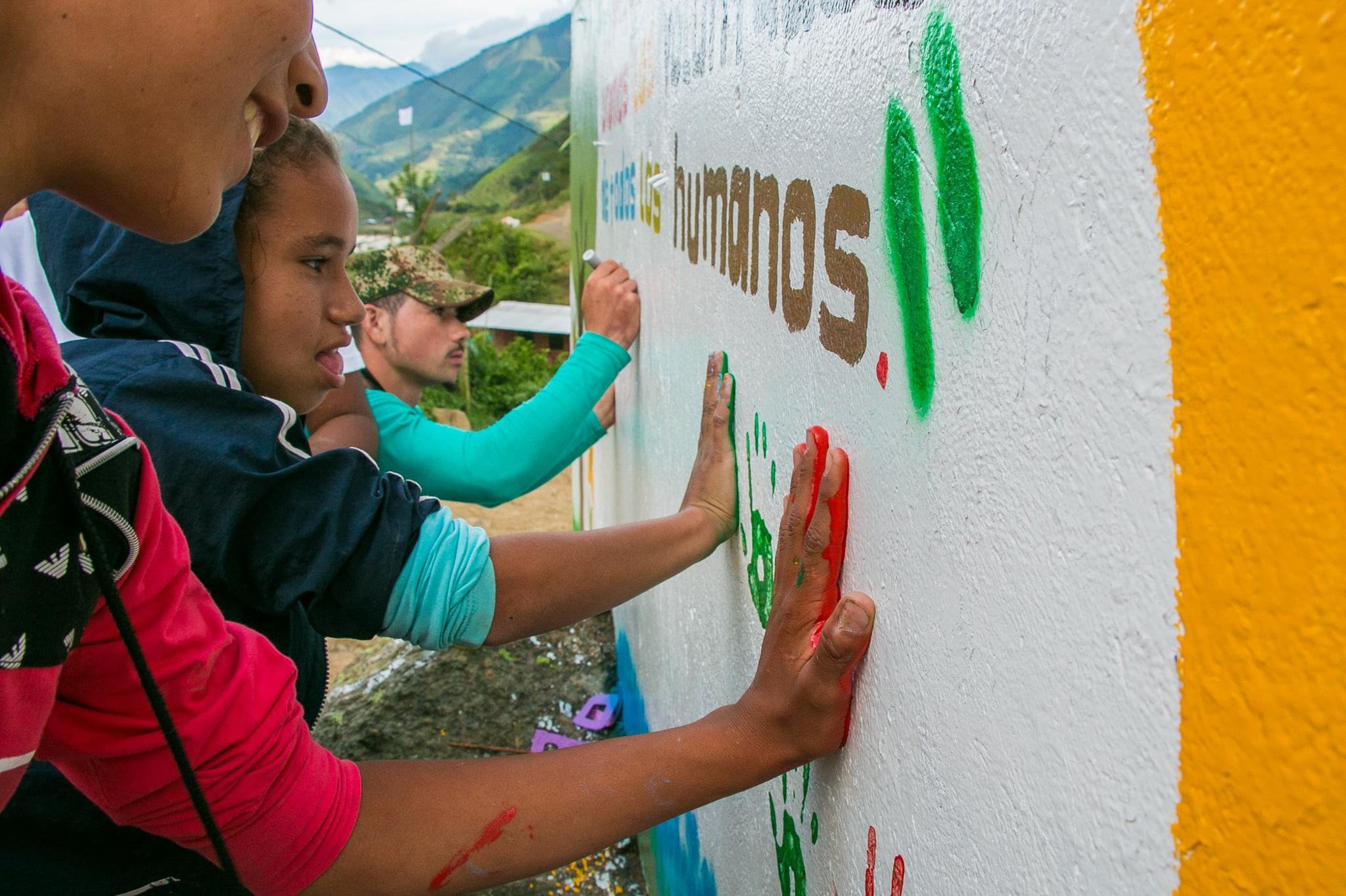 A Farc guerrilla fighter helps children paint a peace mural in Santa Lucia, July 2016.