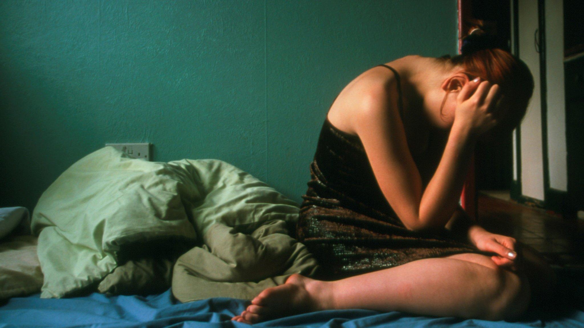 A girl sitting on the floor, hiding her face