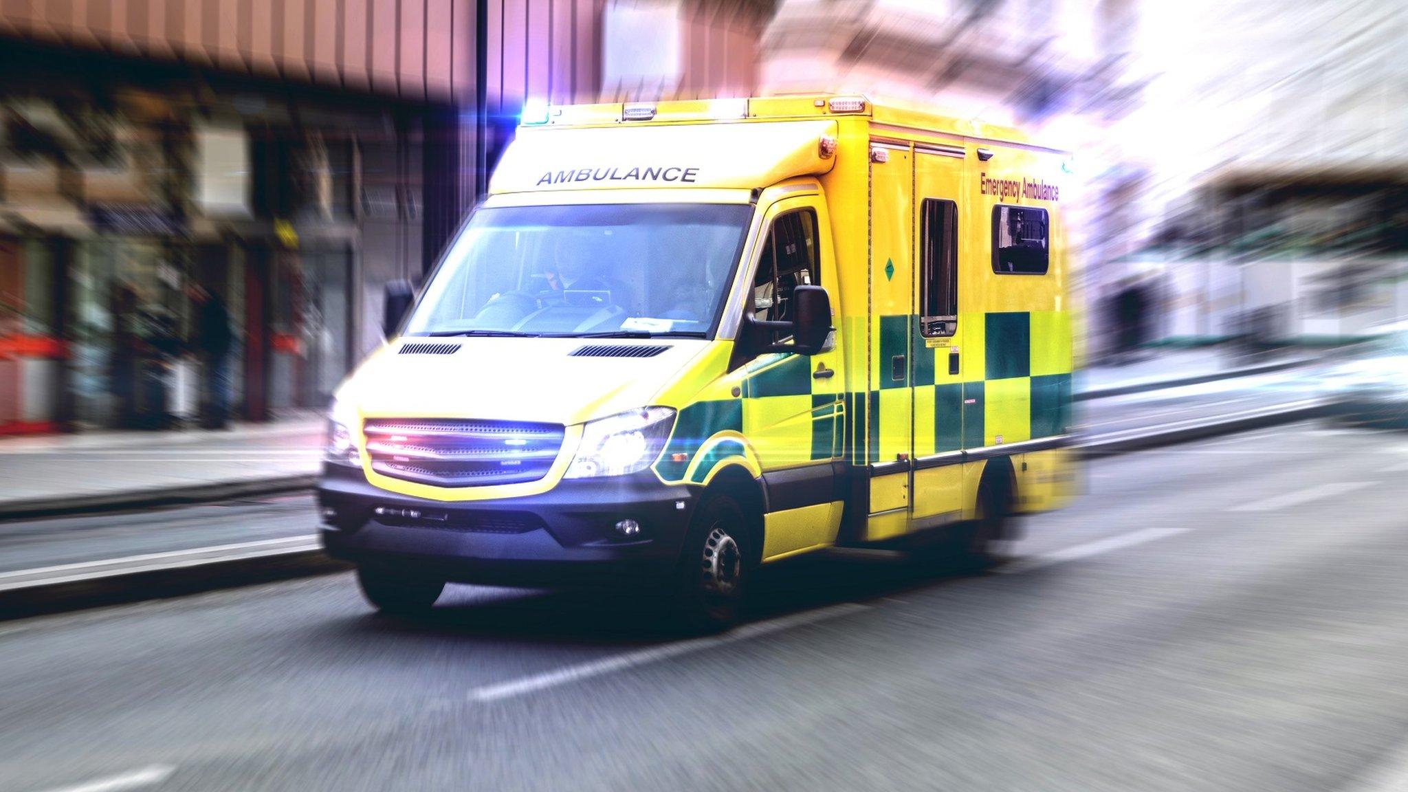 An ambulance driving down a street with its lights on