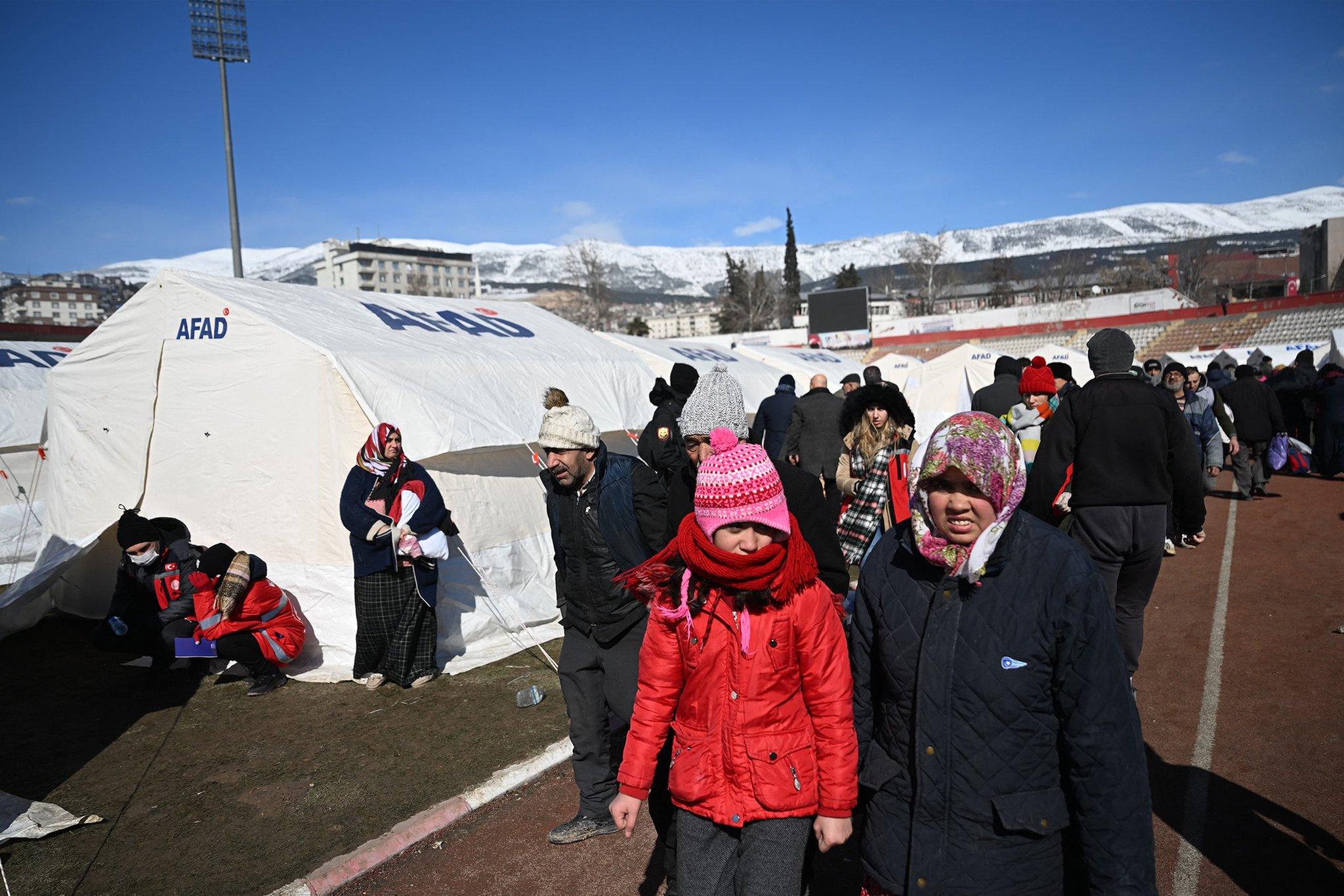 Families walk past tents at a camp set up in Kahramanmaras