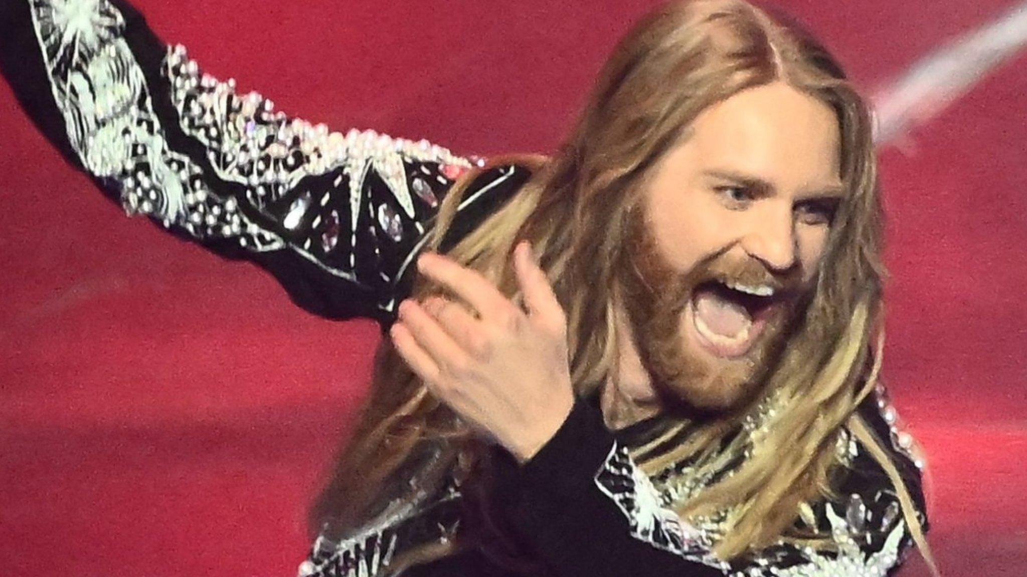 Sam Ryder holding a union flag on stage at Eurovision