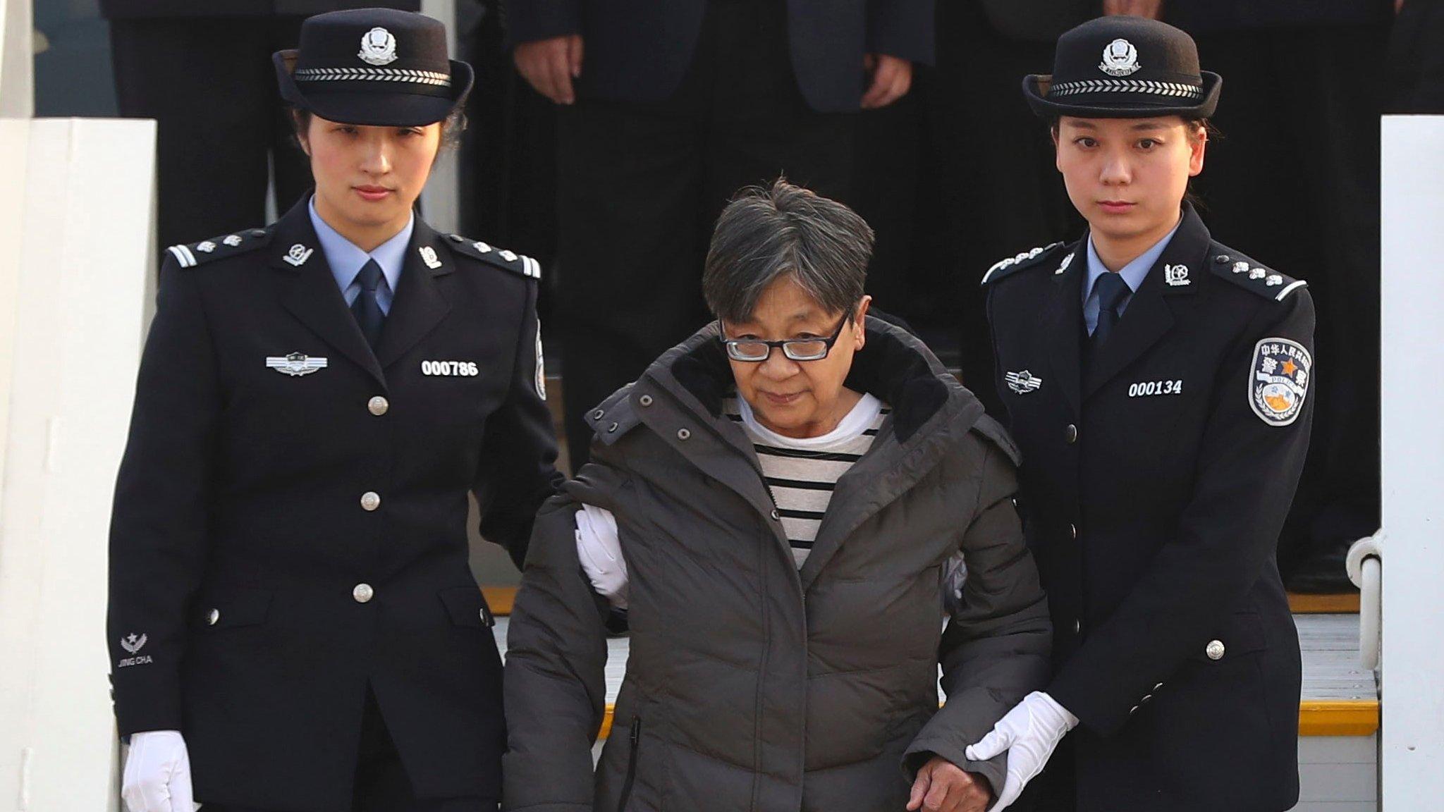 Yang Xiuzhu is escorted down a plane upon arriving at the Beijing Capital International Airport in Beijing (Nov. 16, 2016)