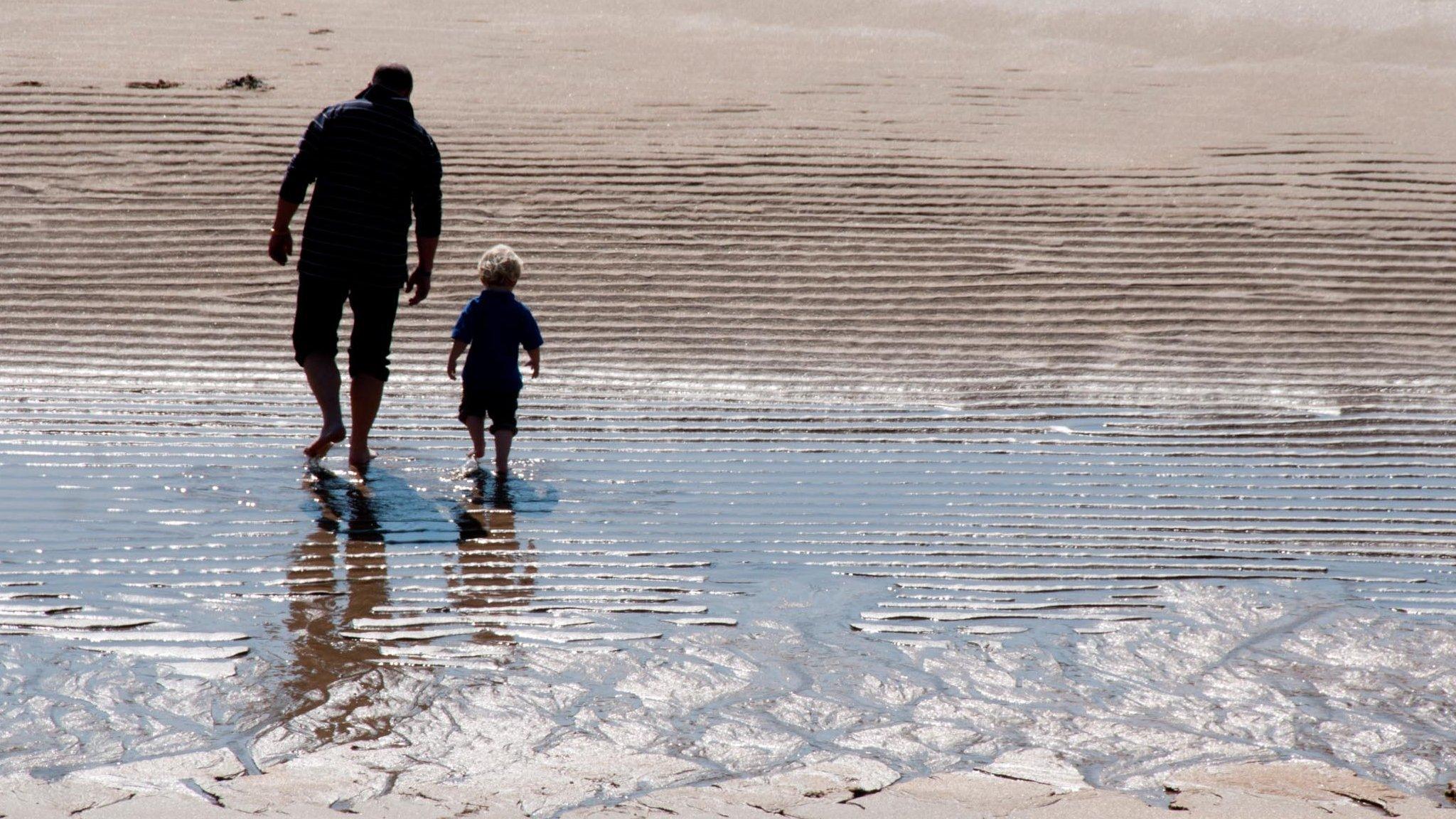 Man and boy walking on beach