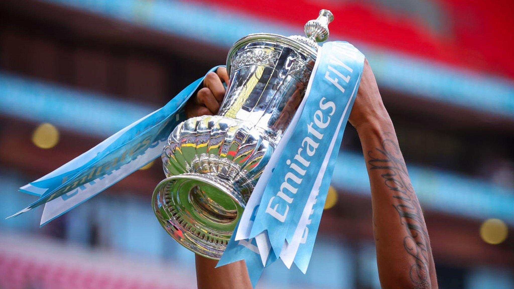 A player holds up the FA Cup