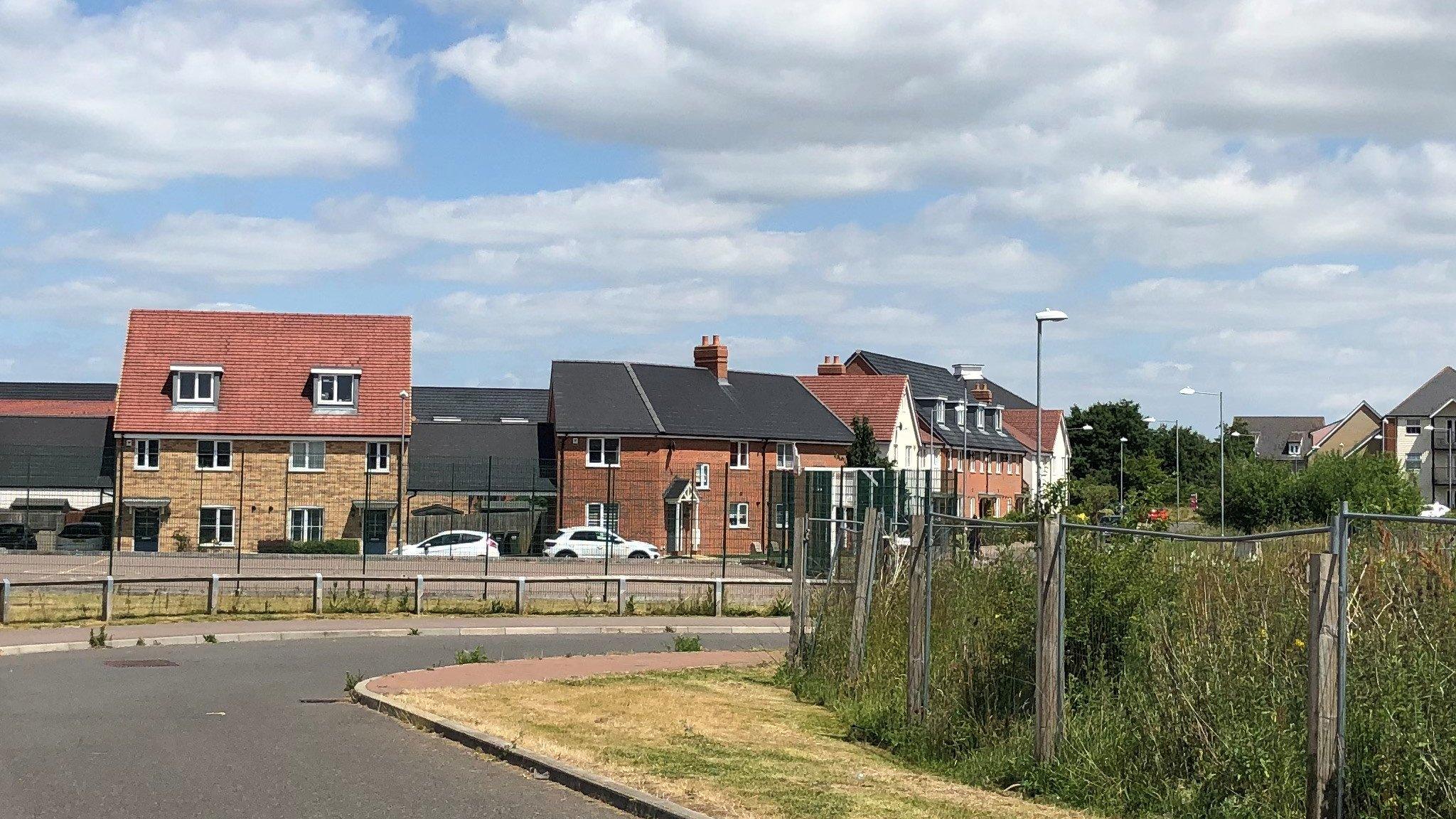 A road between houses and a field