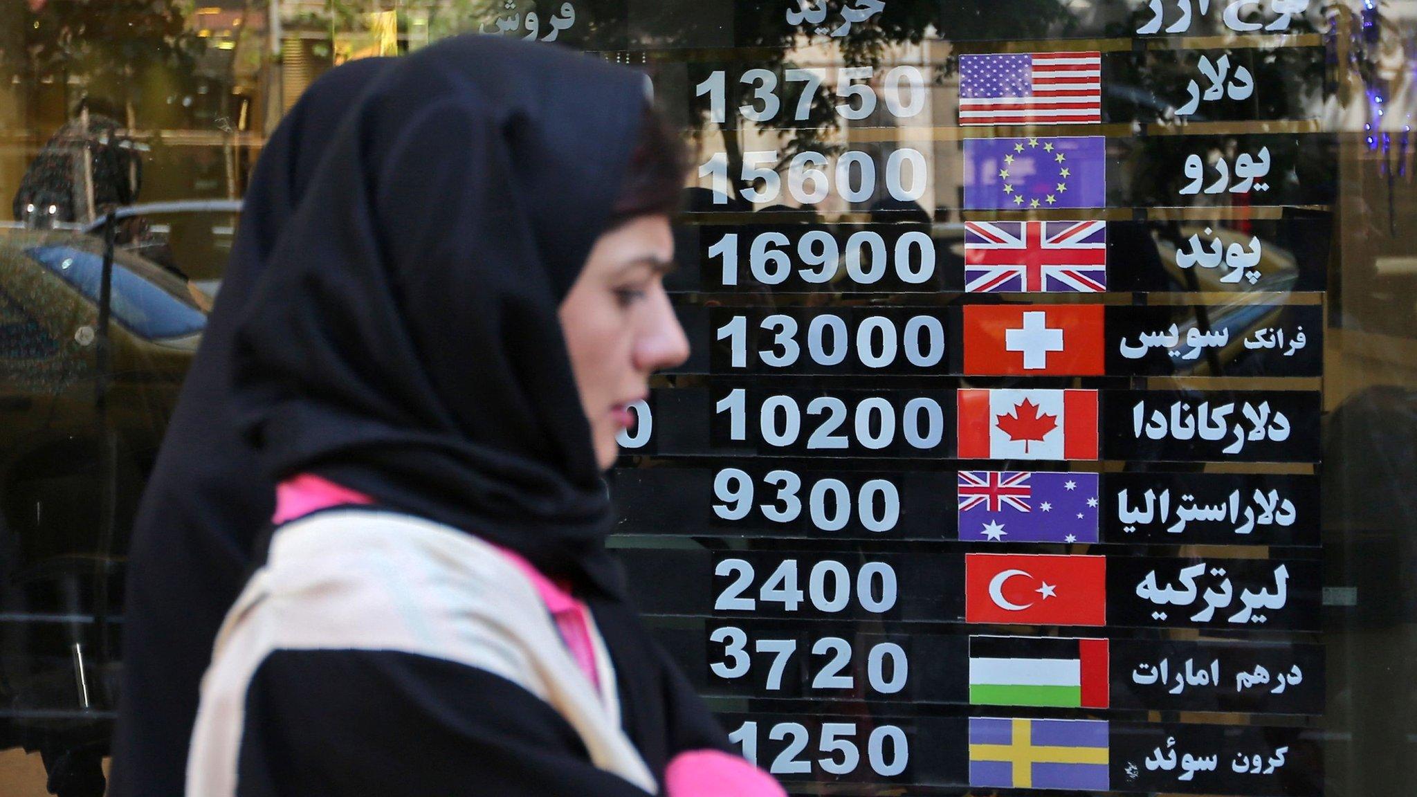 Iranians walk past a foreign exchange shop in Tehran on 22 April 2019