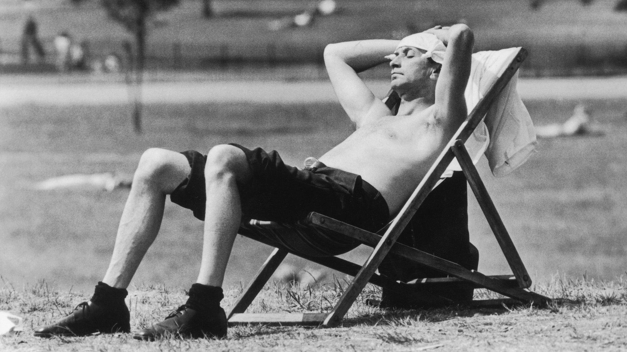 A man sunbathes on a deckchair in Kensington Gardens