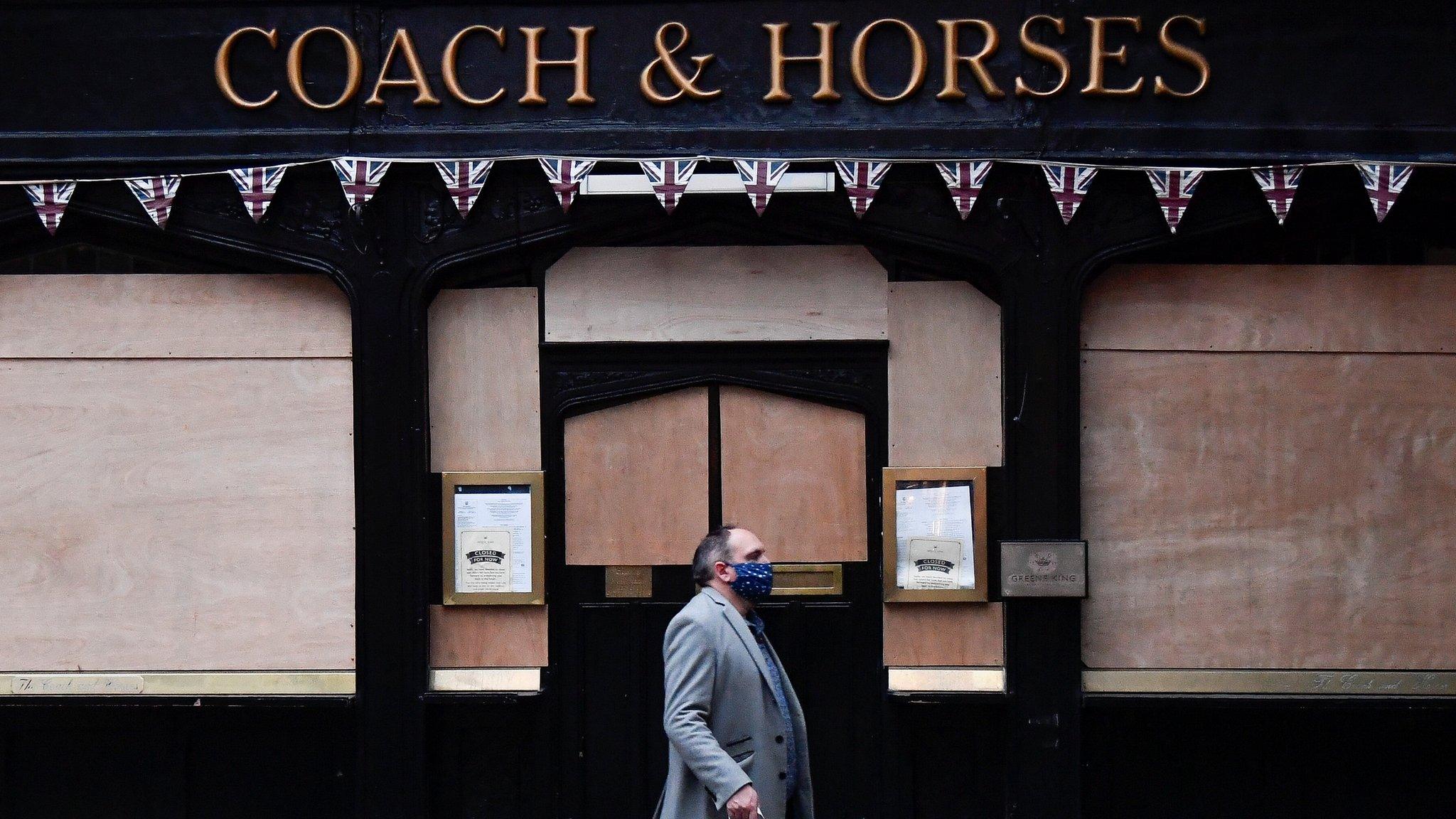 A man walks past a shut-down pub