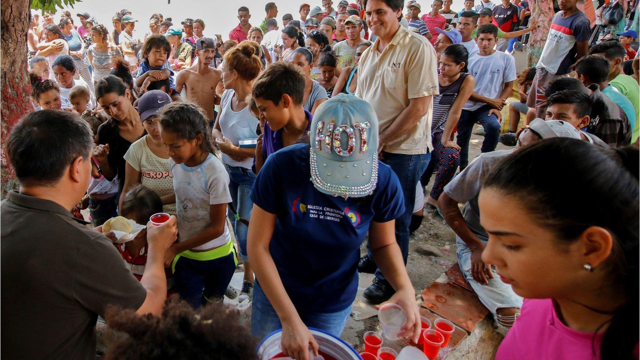 Venezuelan migrants receive food outside a migrant shelter near the Simon Bolivar international bridge in Cucuta, Colombia.