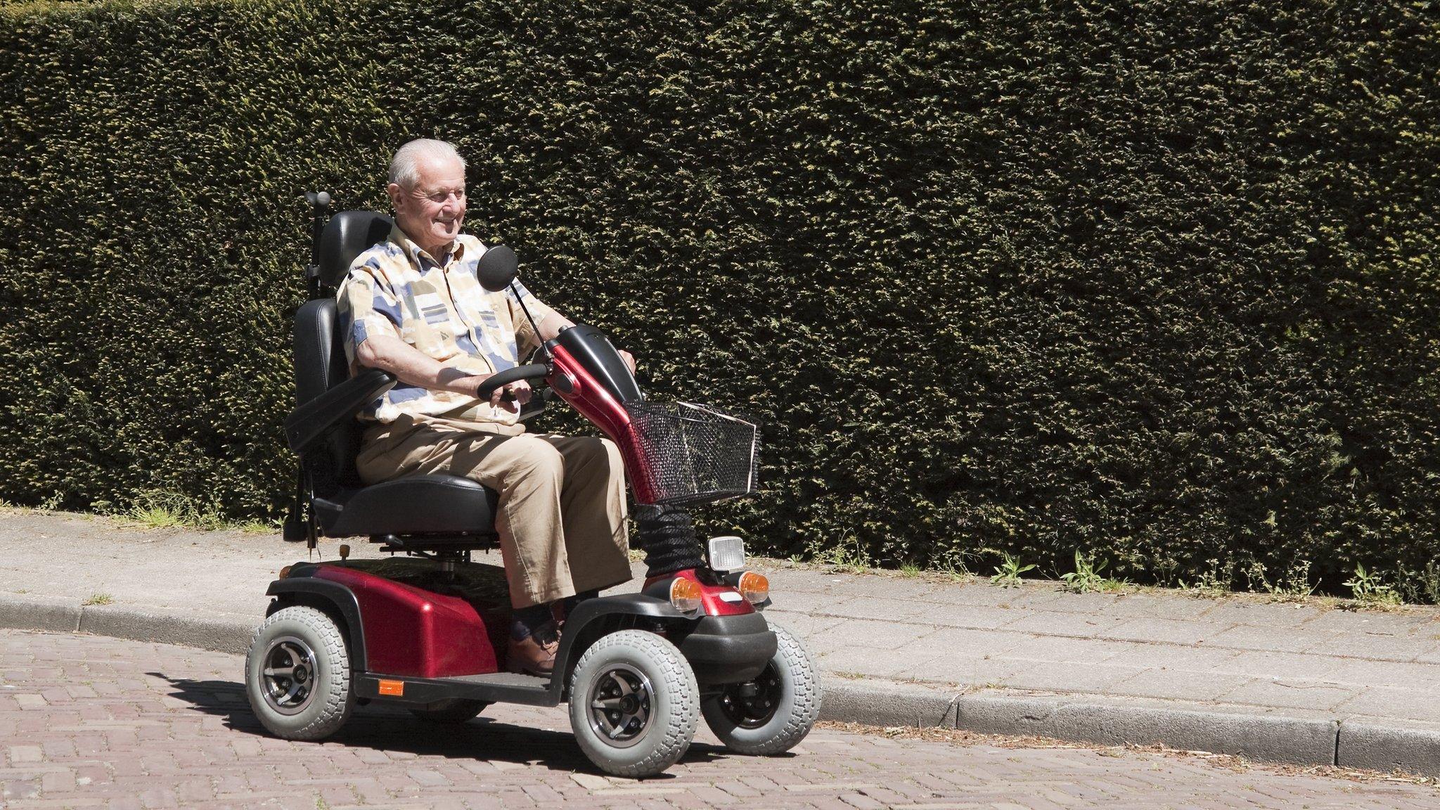 A man in a mobility scooter going down the road