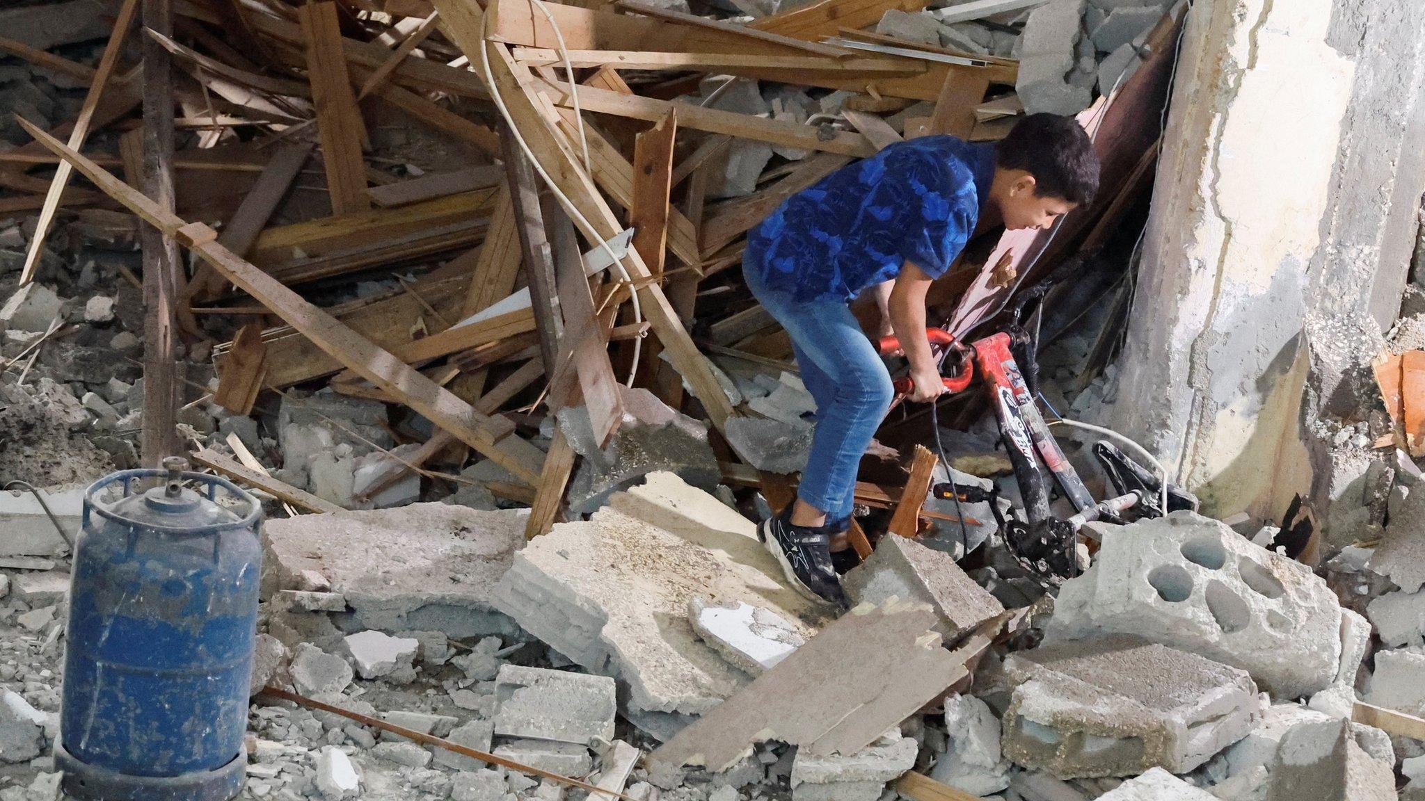 A Palestinian boy pulls a bicycle from rubble at a house damaged during an Israeli raid, in Balata camp, Nablus, in the occupied West Bank (22 May 2023)