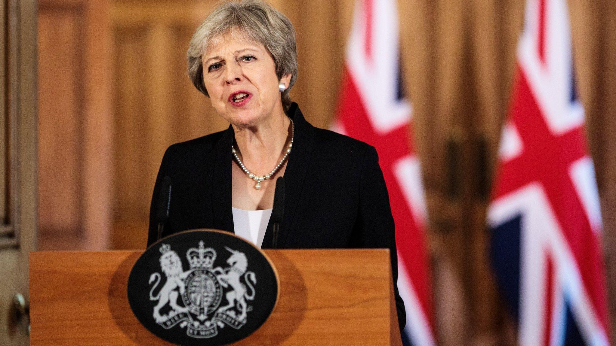 Theresa May stands at podium making speech