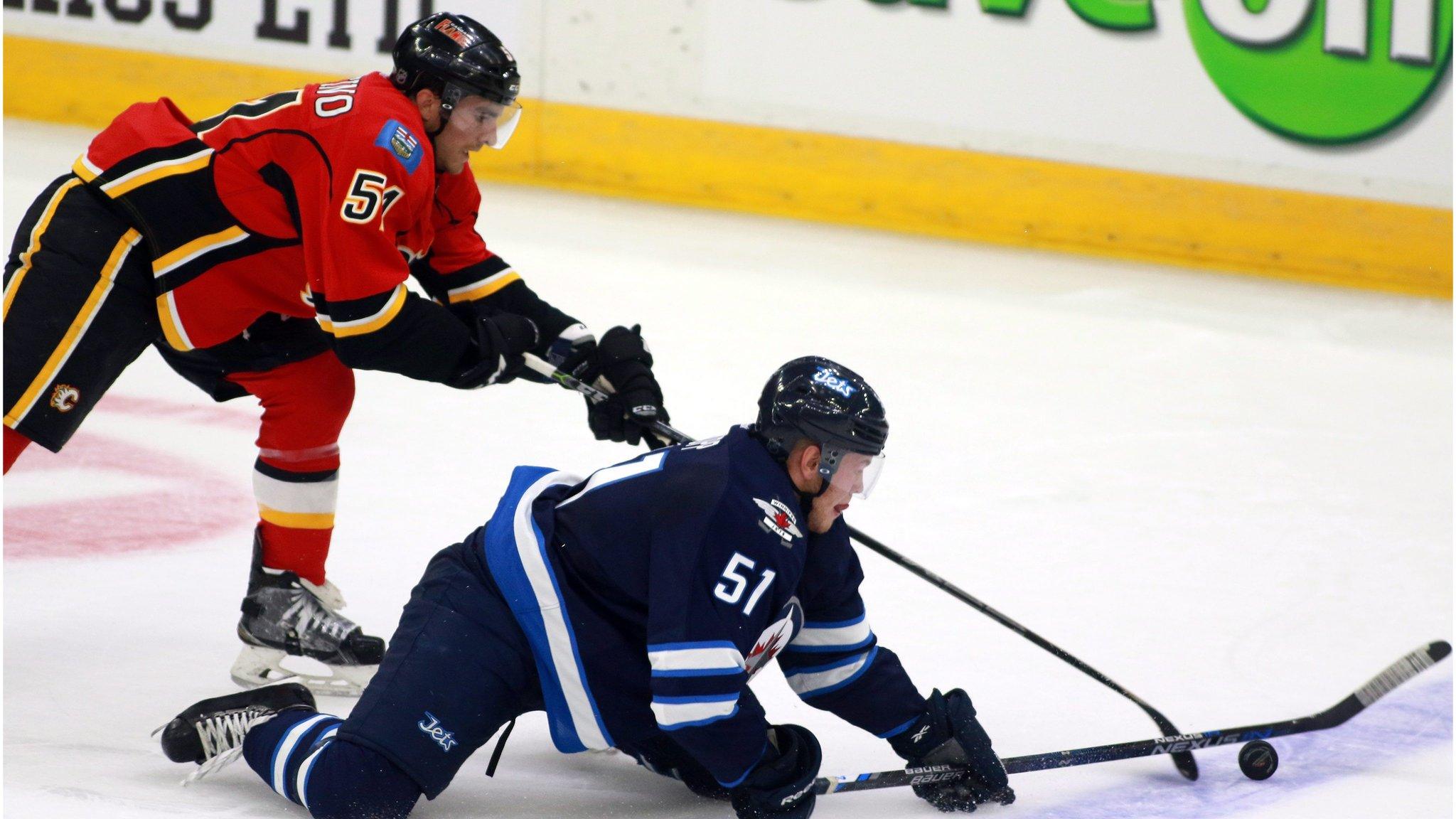 Winnipeg Jets" Andrew Copps (51) tries to control the puck from his knees has Calgary Flames" Kenny Agostino defends during the first period of an NHL hockey rookie game Friday, Sept. 11, 2015, in Penticton, British Columbia