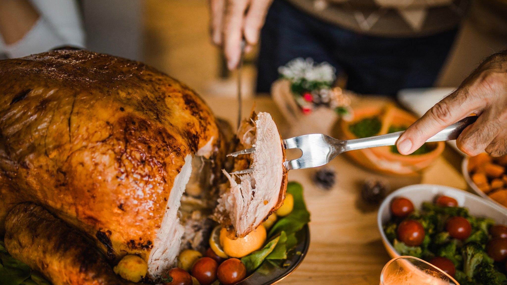 A woman carves a turkey