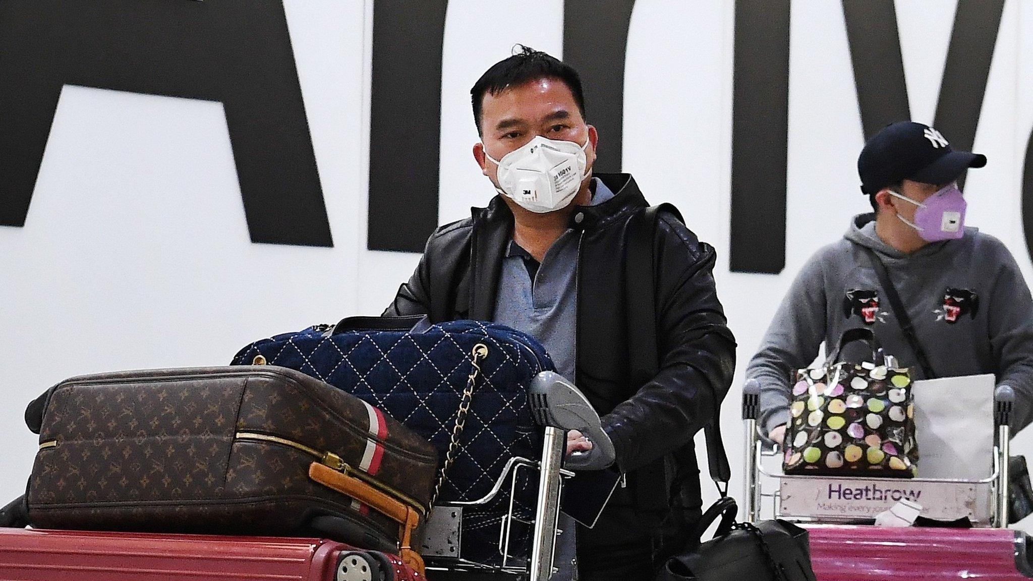 People wearing face masks arrive at London's Heathrow Airport