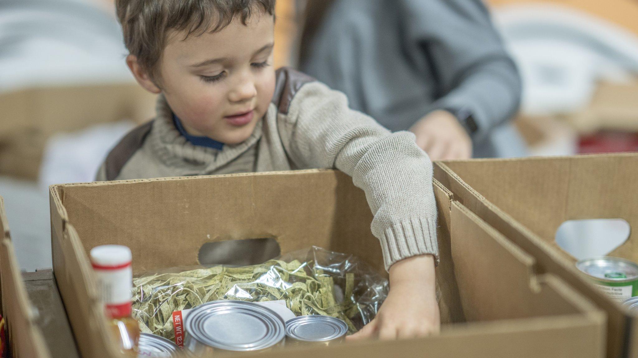 Young boy reaching into food parcel box