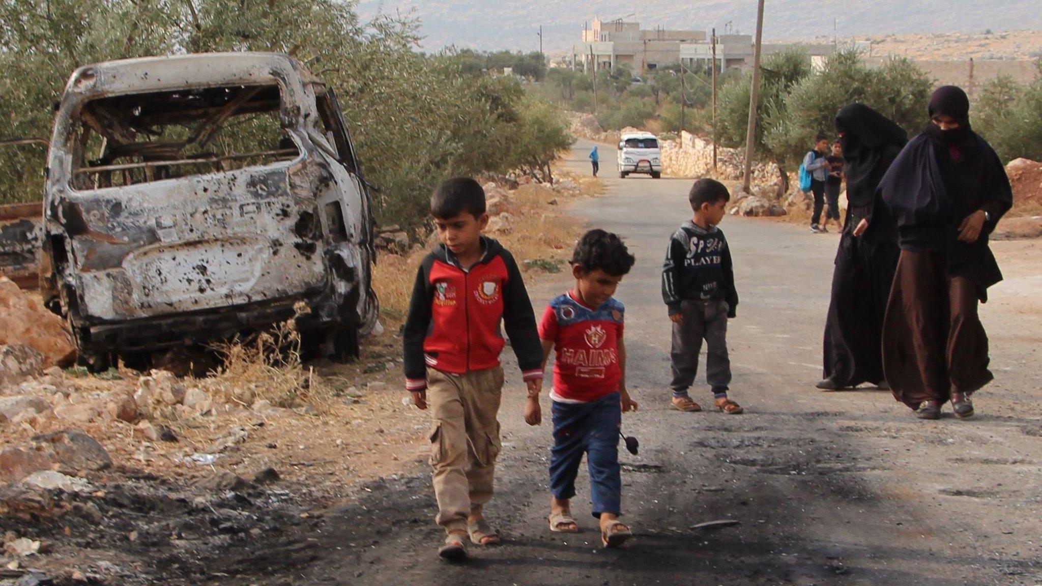 Syrian women and children gather at the site of a US raid near the Syrian village of Barisha (27 October 2019)