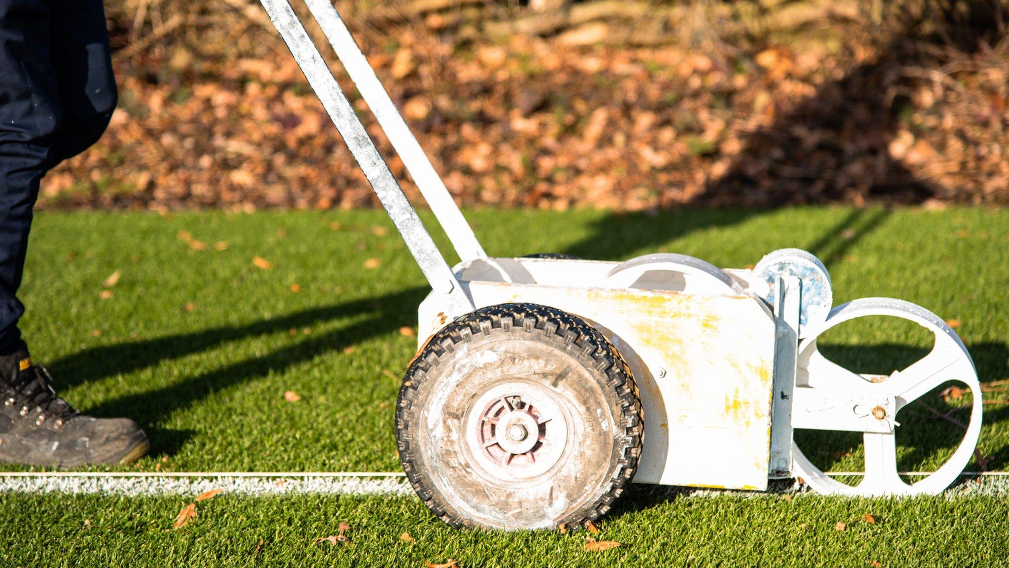 Groundsman paints lines on a football pitch