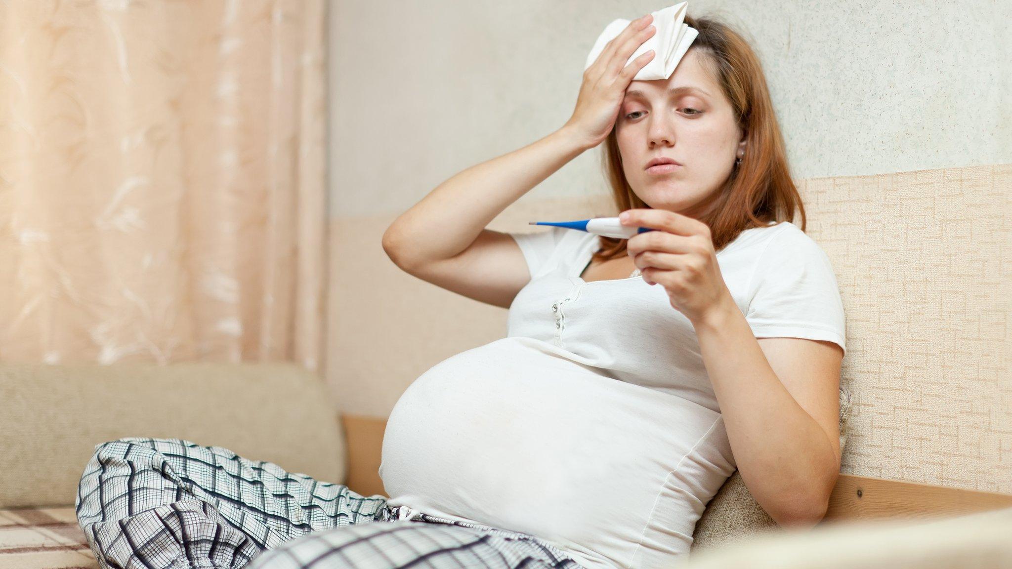 A pregnant woman with a thermometer