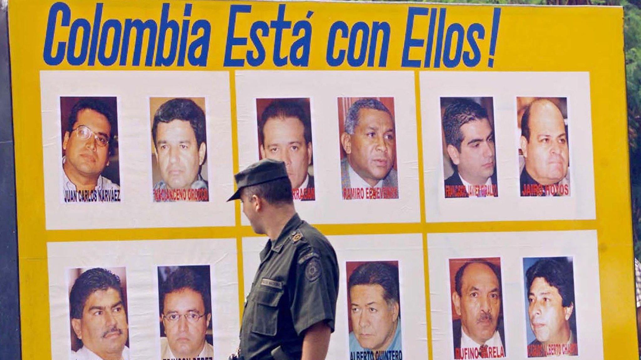 A Cali policeman looks at a billboard 15 April, 2002, showing the 12 provincial deputies kidnapped 11 April by rebels from the Revolutionary Armed Forces of Colombia (FARC) when they stormed the legislative assembly.